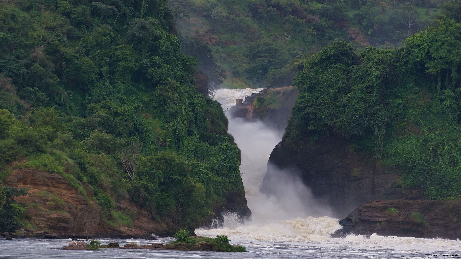 Powerful Murchison Falls: Rushing waters cascade down rocky cliffs amidst lush greenery